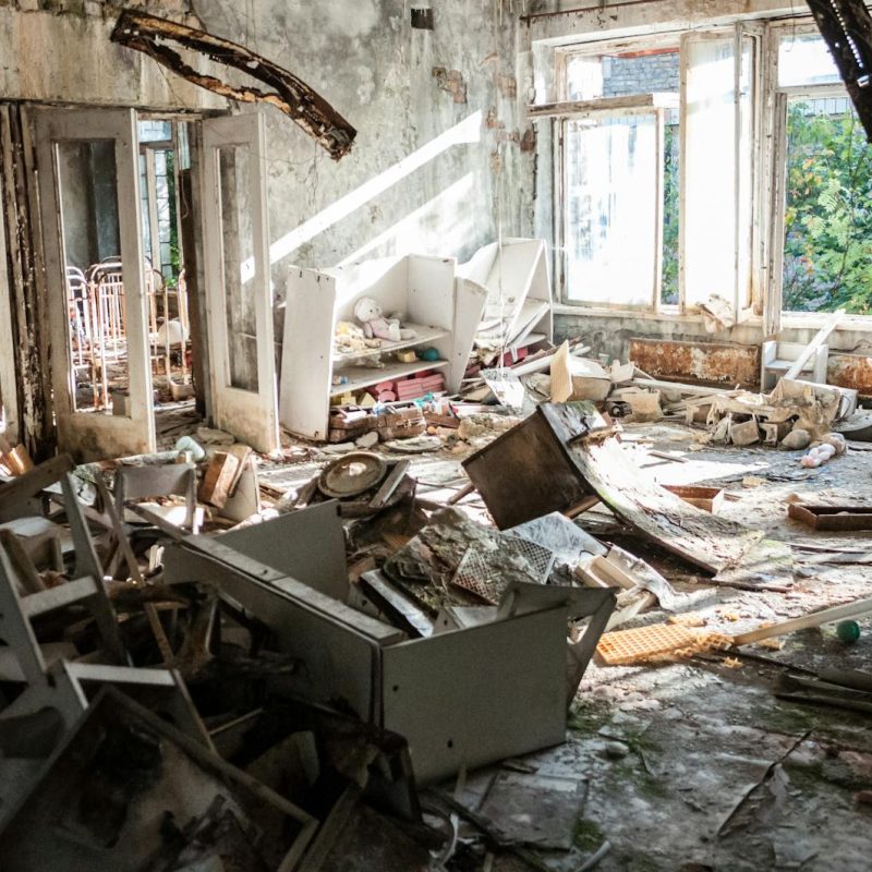A desolate room filled with decayed furniture, debris, and broken windows, illustrating urban decay.